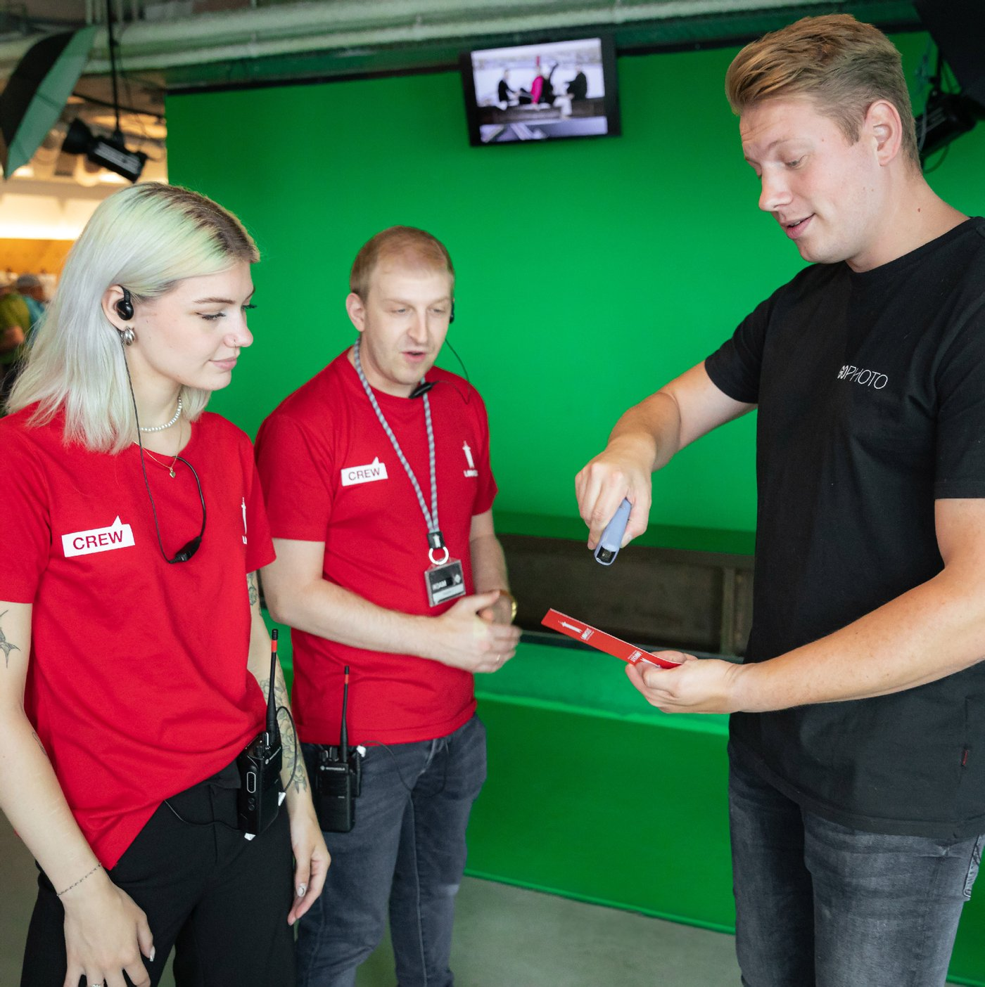 Crew members at the green screen photo point handing a guest the card with the QR code