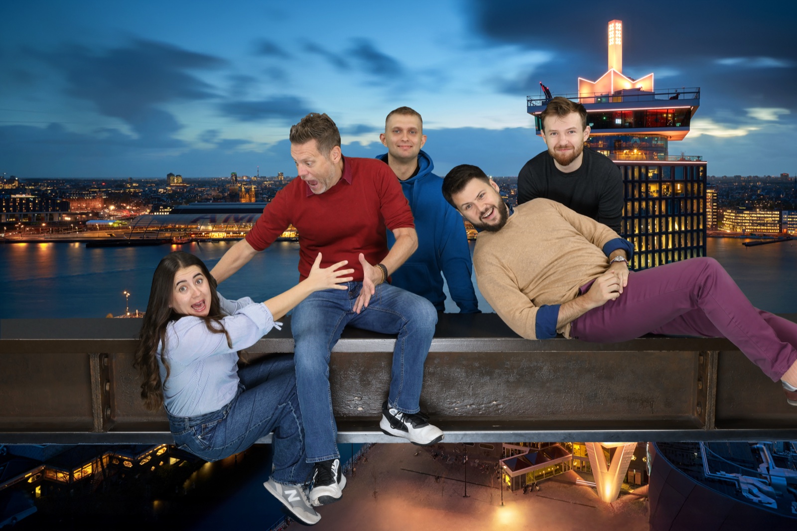 The finished souvenir: the group on the beam above the IJ, with the Amsterdam skyline and the A&rsquo;DAM tower behind them