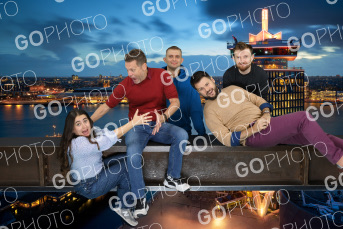Five friends composited onto the ledge at dusk, the city skyline glowing behind them