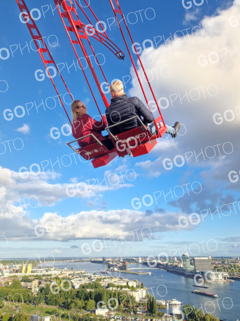A pair seen from behind on the Over The Edge swing, the IJ and Amsterdam's skyline spread out below